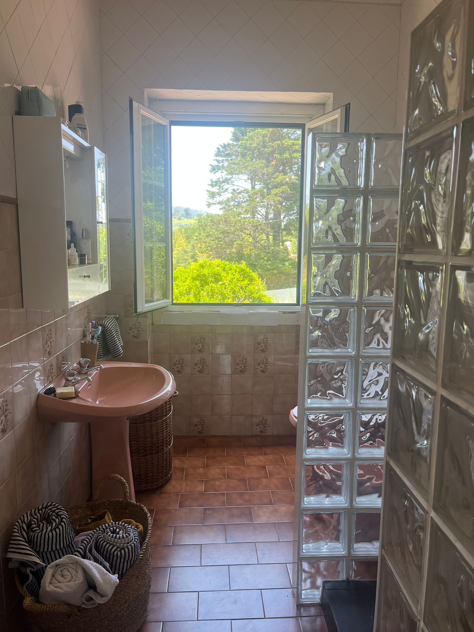 Bathroom with an open window looking onto greenery