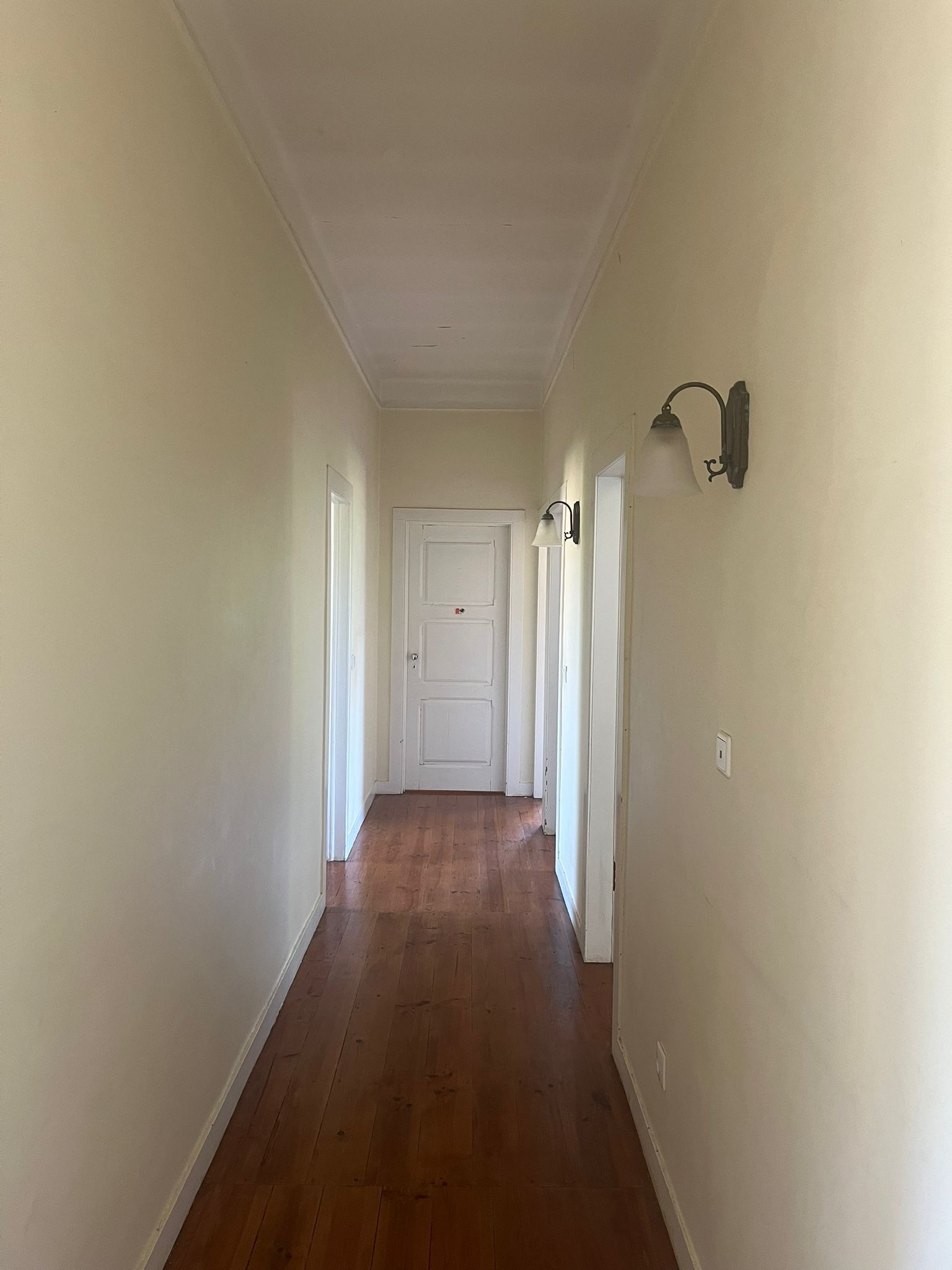Upstairs hallway with wooden floors and wall lights