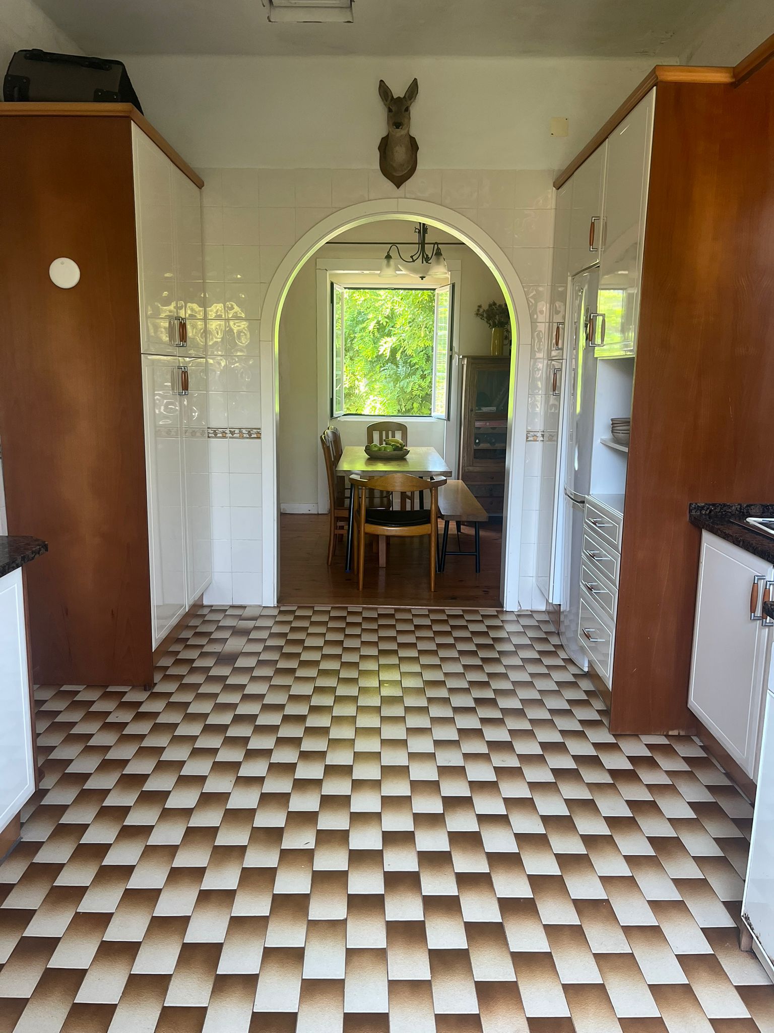 Kitchen with checkerboard floor and arched doorway to dining room