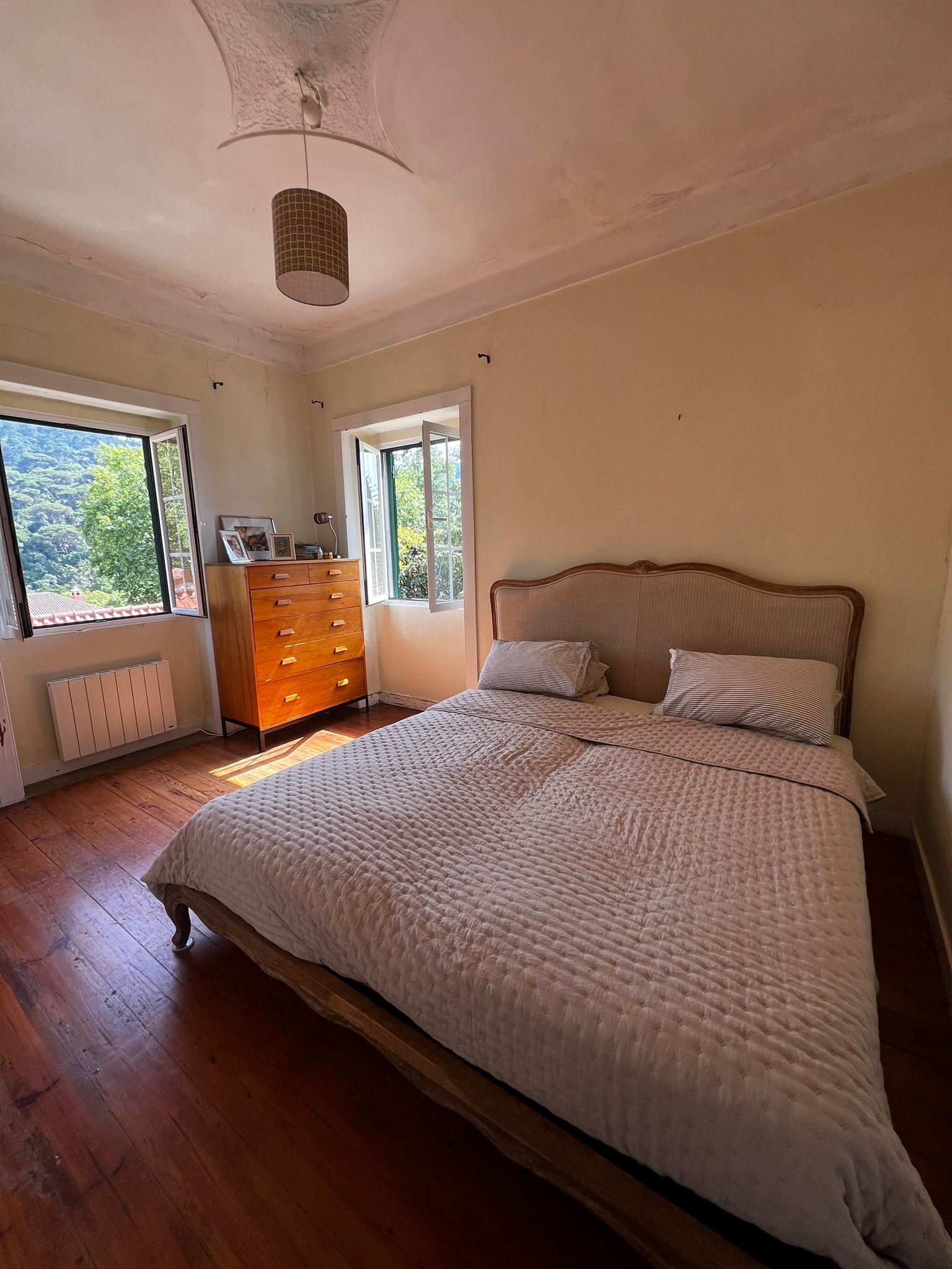 Double bedroom with wooden floors, open windows and old-house details
